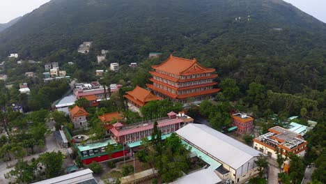 Toma-De-Drones-De-Un-Gran-Templo-Budista-Chino-En-Un-Pequeño-Pueblo-Con-Un-Bosque-Y-Una-Montaña-Alrededor-Durante-El-Día