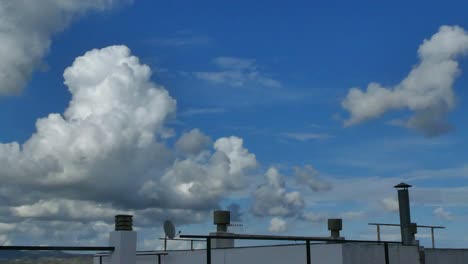 the roof of a building and white clouds passing