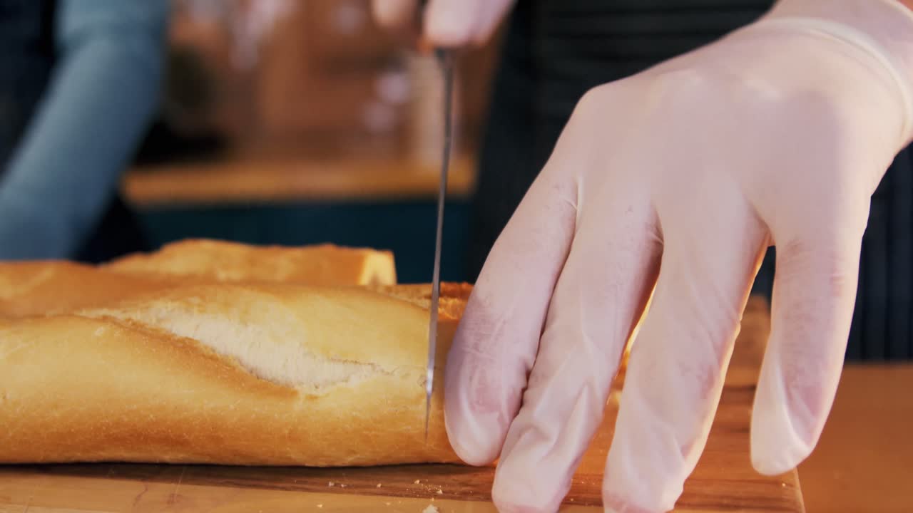 Waiter cutting loaf of bread