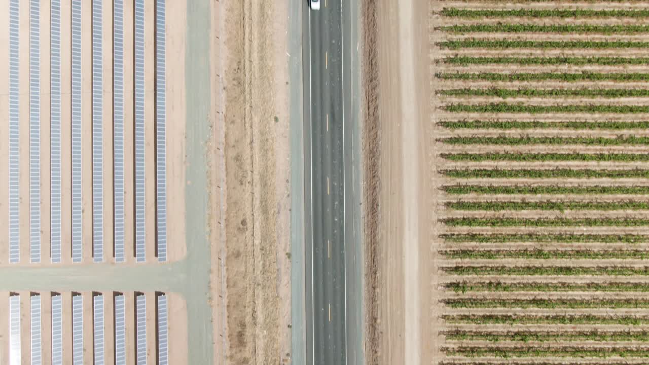 vista de pájaro a gran altitud sobre un camino rural en el campo con paneles solares en el lado izquierdo y un viñedo en el lado derecho