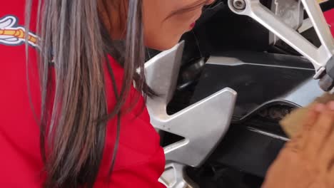 woman inspecting and cleaning motorcycle chain