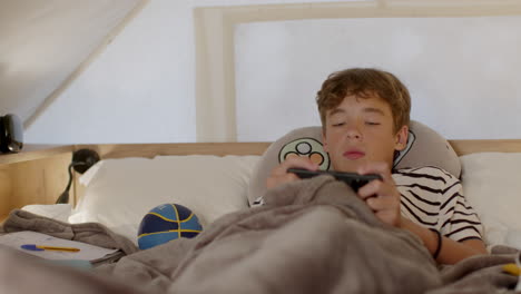 teenager relaxing in bed, playing games on smartphone