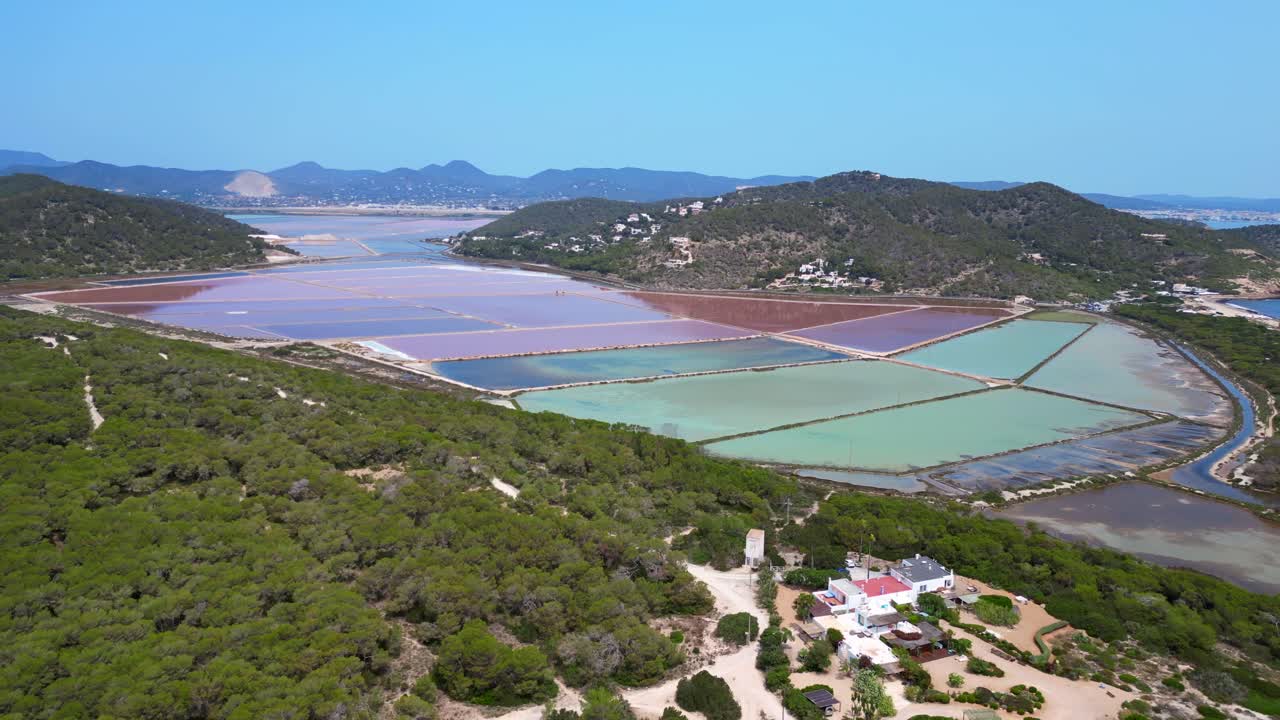 colorful salt flats of Ibiza with the Mediterranean vegetation in the foreground. Majestic aerial view flight fly reverse drone