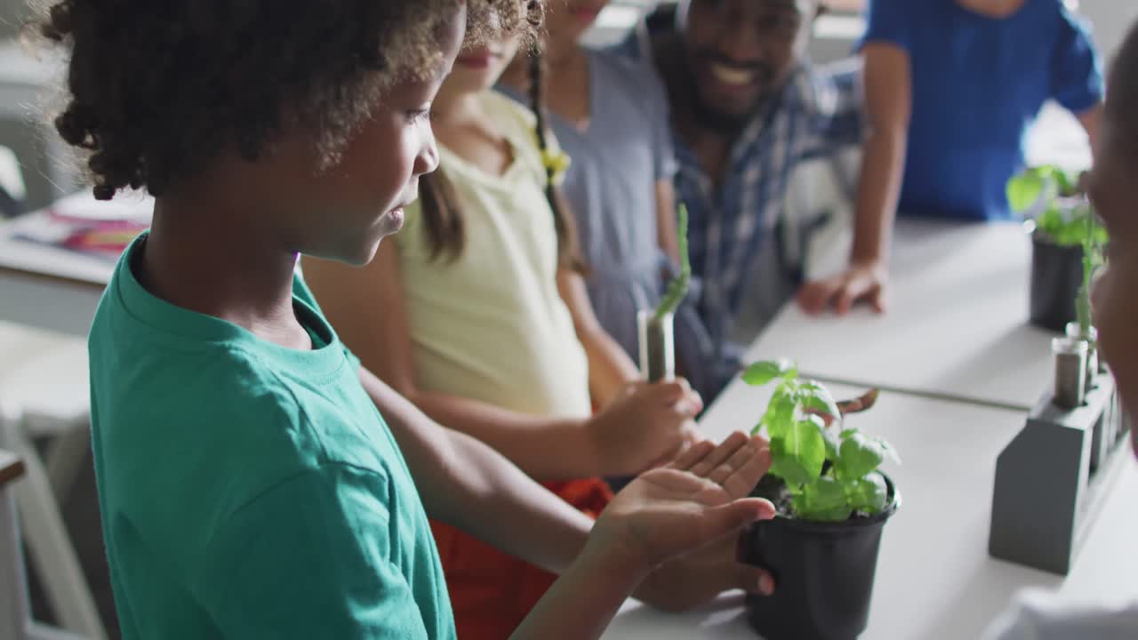 Video of happy african american male teacher and class of diverse pupils during biology lesson