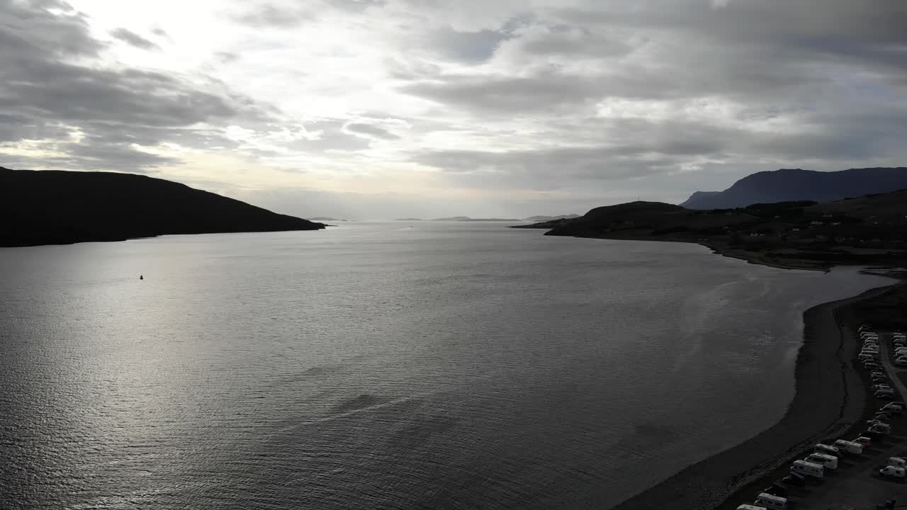 toma aérea de la escoba del lago al atardecer cerca de ullapool en las tierras altas escocesas con montañas a ambos lados