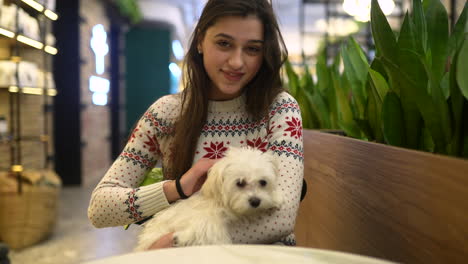 young woman with a maltese dog in a cozy cafe