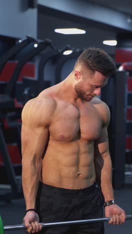 strong athlete lifting barbell in gym. handsome man doing exercise with a heavy barbell. sportsman doing strength and endurance exercises with barbell. weightlifting. vertical video