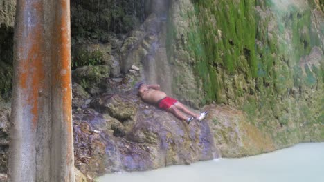 man relaxing under a waterfall at tumalog falls in cebu, philippines