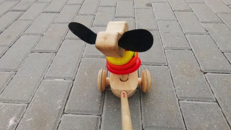 wooden toy puppy with wheels rides through the pavement