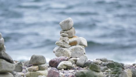 zen meditation background - balanced stones stack close up on a rocky sea beach surrounded by beautiful waves