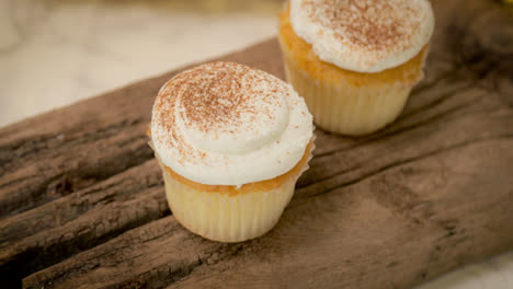 pumpkin spice cupcakes on a piece of driftwood with a marble countertop