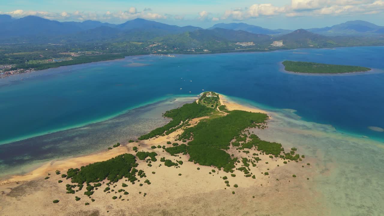 Ripresa cinematografica con drone di Cowrie Island a Palawan, Filippine. Vista dall'alto del banco di sabbia tropicale, della vegetazione lussureggiante e dell'oceano cristallino con montagne sullo sfondo.