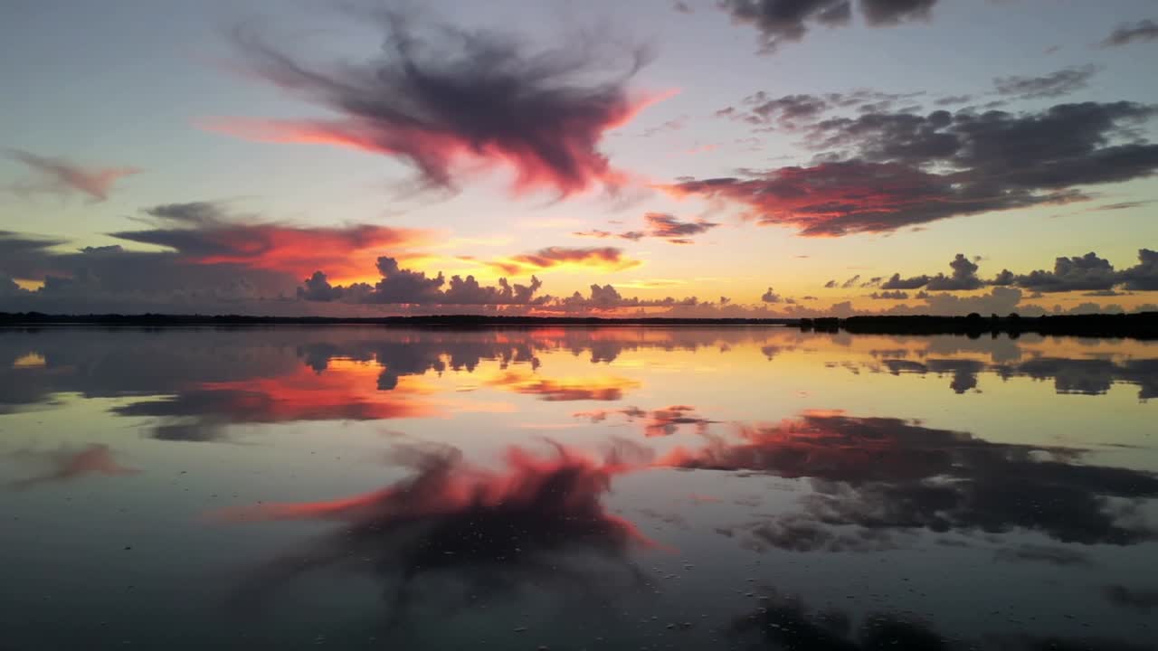Catturare il riflesso del cielo al tramonto che cambia mentre il sole cala su una laguna costiera, con una nuvola rosa alla deriva.