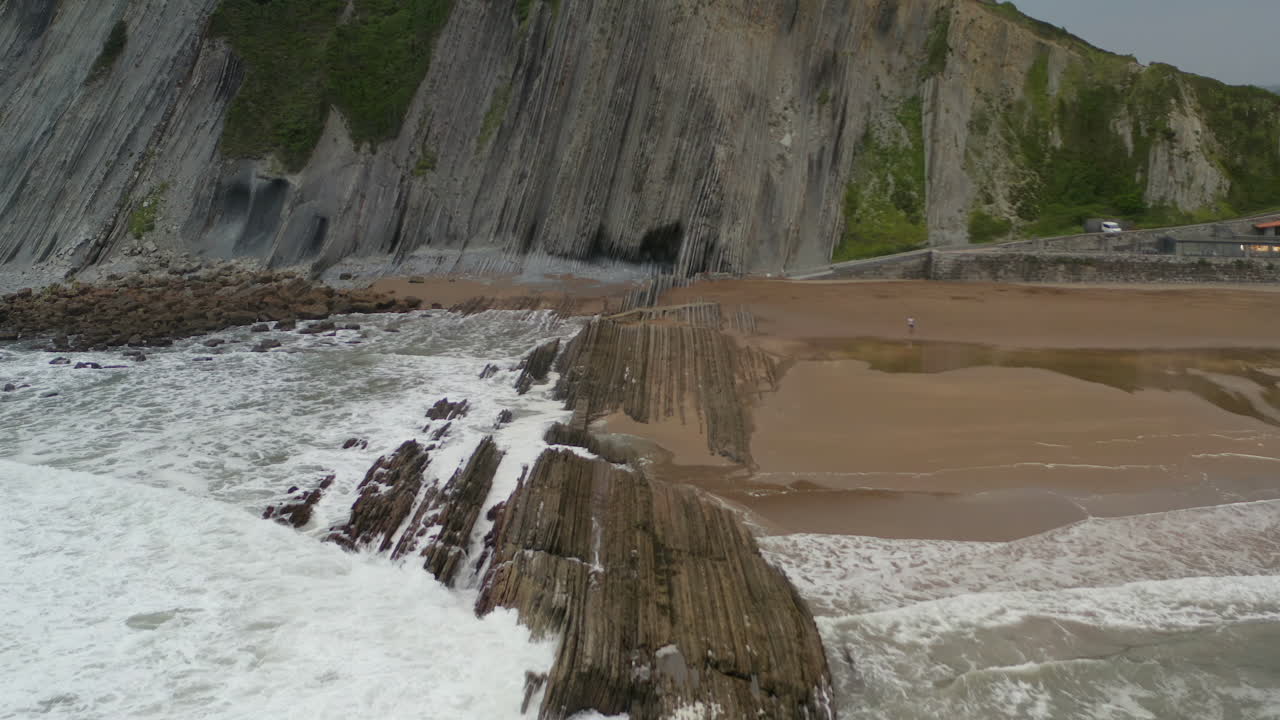 las olas del océano chocan contra una formación geológica única en la playa de itzurun, españa.