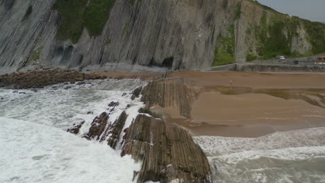 ozeanwellen stürzen sich auf eine einzigartige geologische flysch-formation an einem strand in spanien.