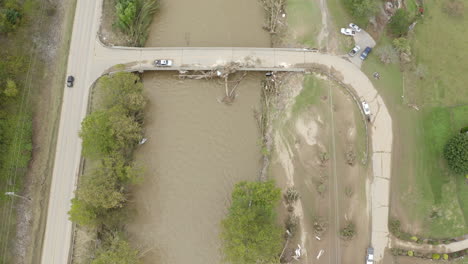 tropical storm damage aftermath of hurricane helene in waynesville, north carolina with fallen tree on bridge river damage from flood aerial drone view