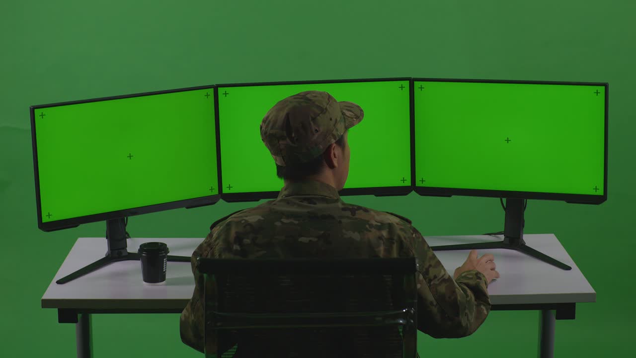 Soldado Descansando em um Computador com Monitores de Tela Verde