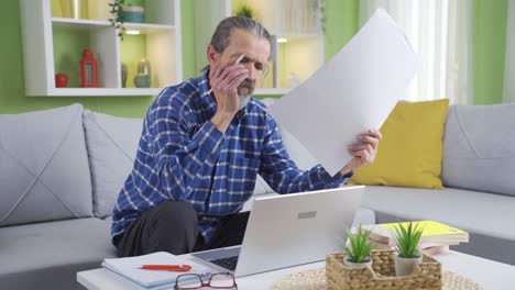 hombre independiente de mediana edad que trabaja en la sala de estar en casa usando una computadora portátil.