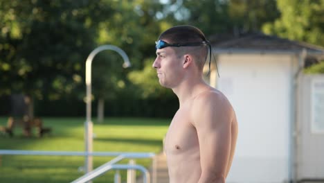 young athletic swimmer walks into the frame looking at the water