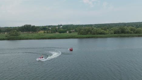 Bewegung-Nach-Rechts-Entlang-Des-Flusses,-Wo-Urlauber-Mit-Dem-Wasserfahrrad-Fahren,-Blick-Auf-Das-Grün