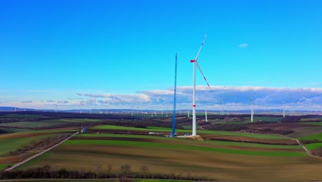 construction of wind turbine with crane in the field - aerial drone shot