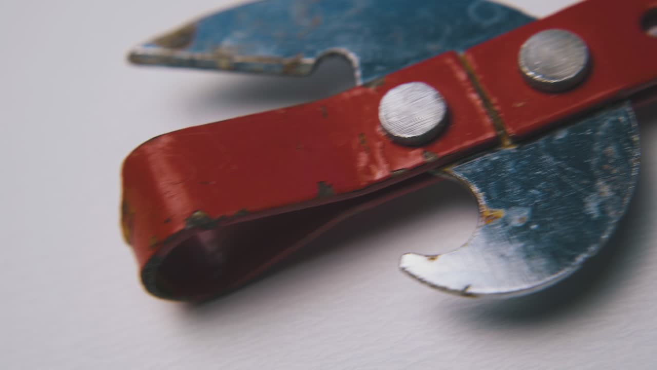 abridor de latas de movimiento pasado con mango rojo en superficie blanca