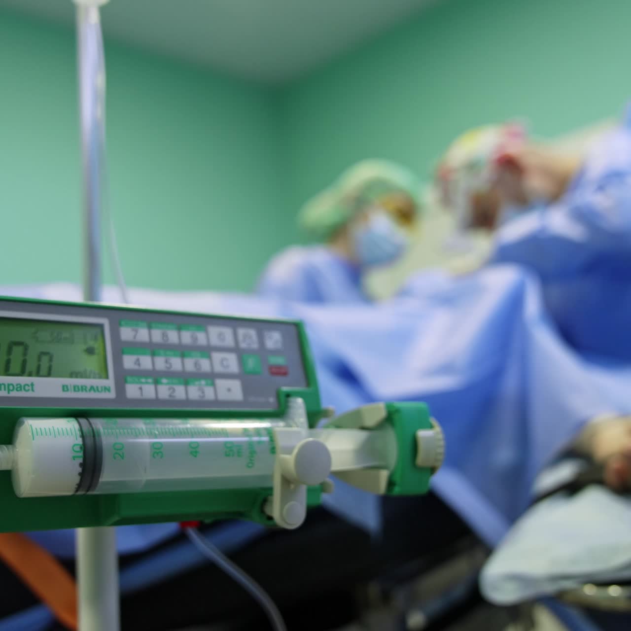 Infusionsmaschine für Medikamente. Gerät im Betrieb. Nahaufnahme. ChirurgInnen im verschwommenen Hintergrund