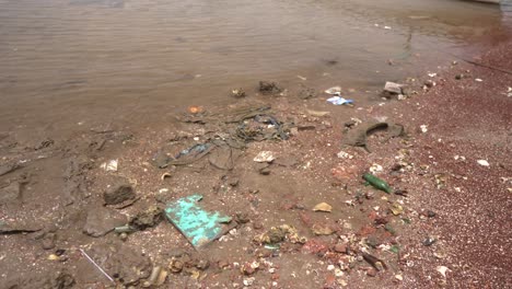 Una-Playa-Llena-De-Escombros-Dispersos-Y-Una-Costa-Rocosa-Distante-En-Un-Día-Nublado