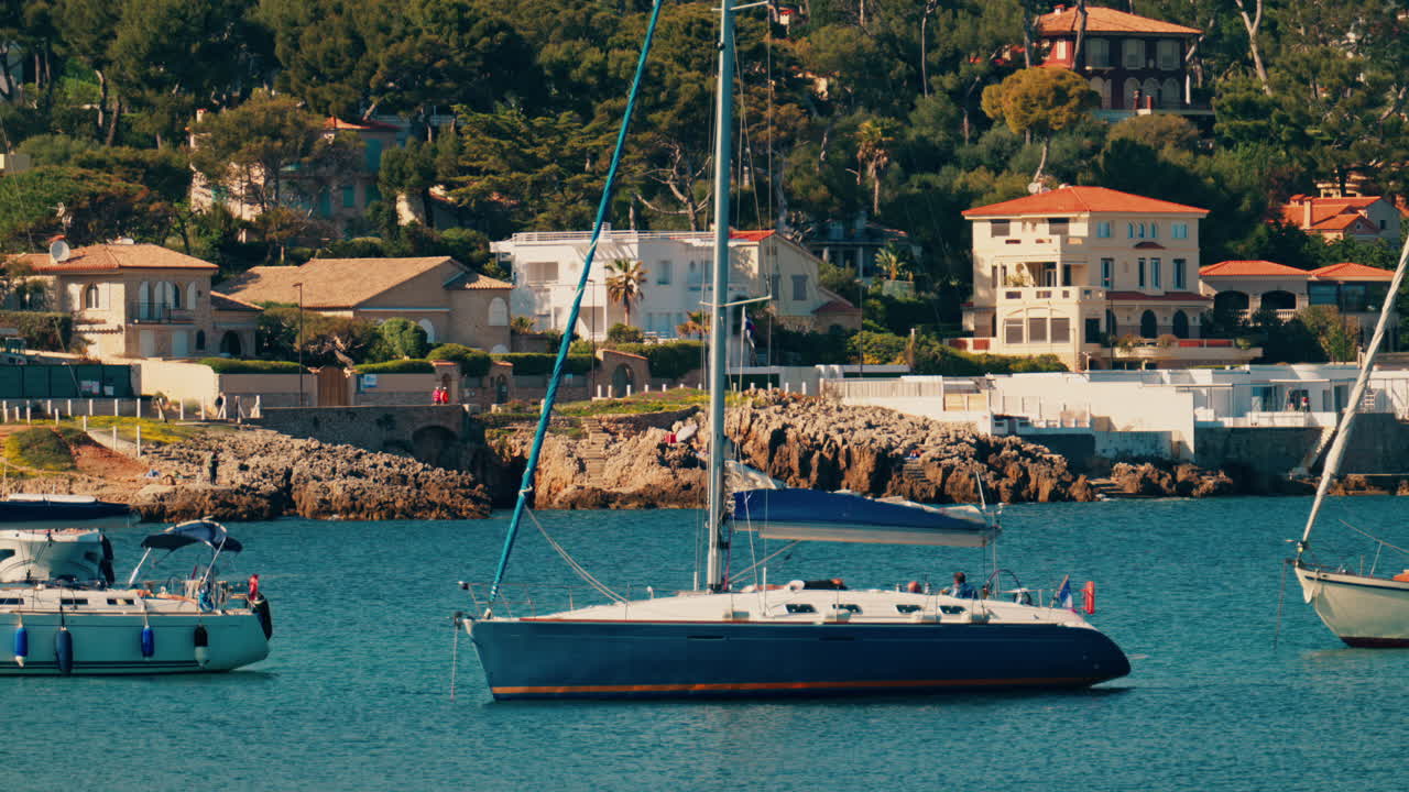 Boats docked on the sea with villas surrounded by greenery in the background