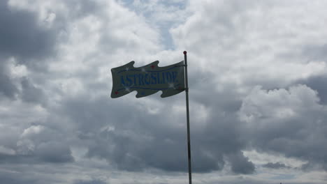 An-astro-slide-sign-on-a-flagpole-on-a-cloudy-day