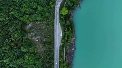 panoramic road between green forest and banks of lake with turquoise and calm waters