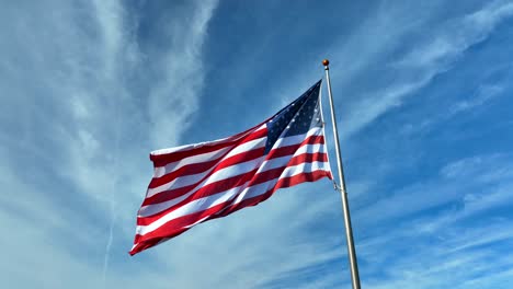 american flag waves in breeze against blue sky