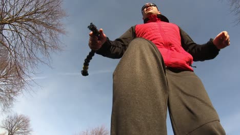 hombre de mediana edad sosteniendo un soporte de extensión gopro y patinando, tiro pov
