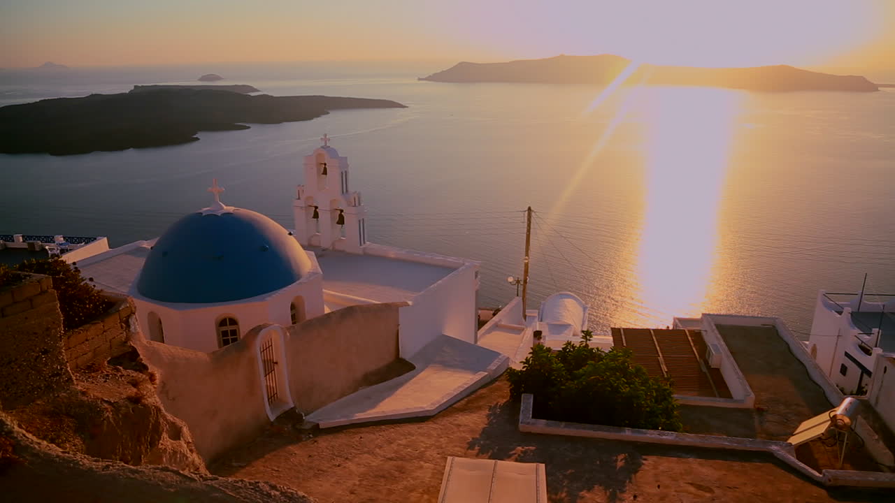 una hermosa puesta de sol detrás de una iglesia ortodoxa griega en la isla griega de santorini