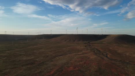 Toma-Aérea-De-Un-Parque-Eólico-Con-Turbinas-Eólicas-Sobre-Altas-Colinas-Al-Atardecer,-Australia-Del-Sur