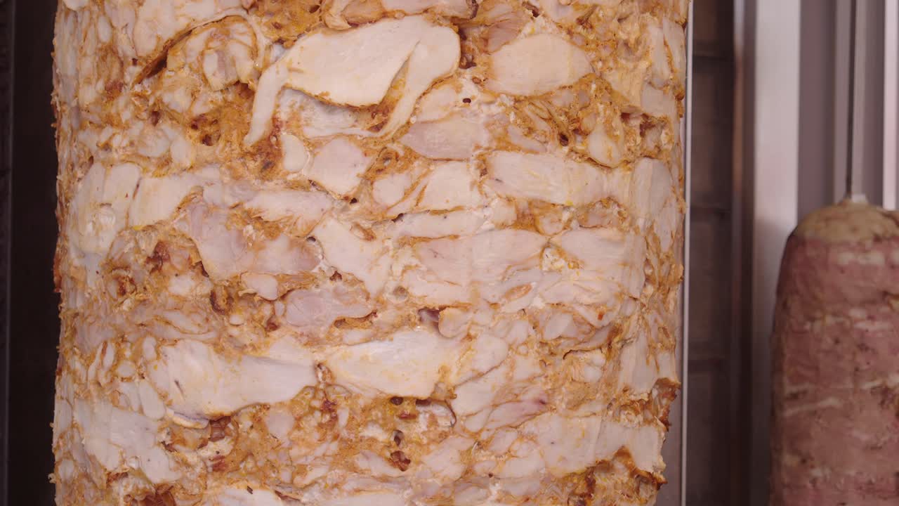 Close-up of rotating chicken doner kebab meat on a vertical spit