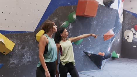 unrecognizable women standing near climbing wall in gym