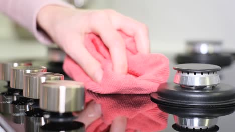 a woman wipes dust on a gas stove cleaning in the kitchen close up