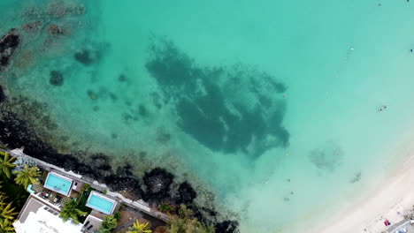 Aerial-top-down-of-rocky-sea-shore,pool-area-and-transparent-turquoise-ocean
