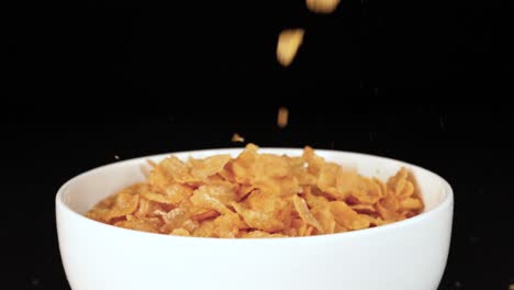 golden cereal flakes cascade into a white bowl, set against a dark backdrop, creating a dynamic and appetizing visual