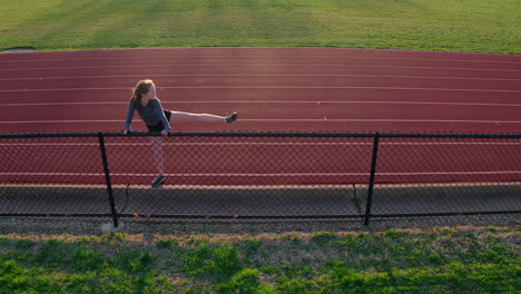 teen girl athlete stretches and warms up her legs before a run at the track