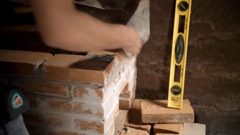 worker in small mud hut working to install brick stove