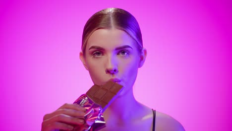 nordic young blonde makeup woman eats a chocolate suggestively in a studio, close up shot