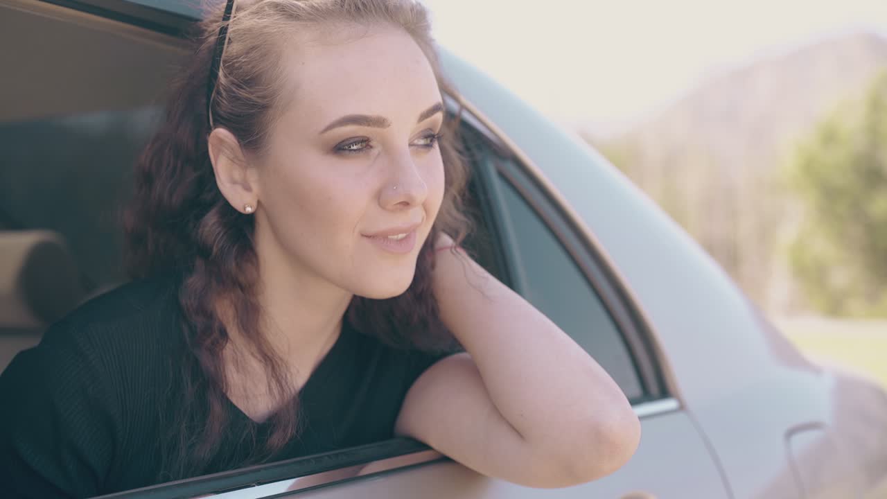 привлекательная девушка с легким макияжем откидывается от автомобиля