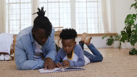 father and son reading a book together at home