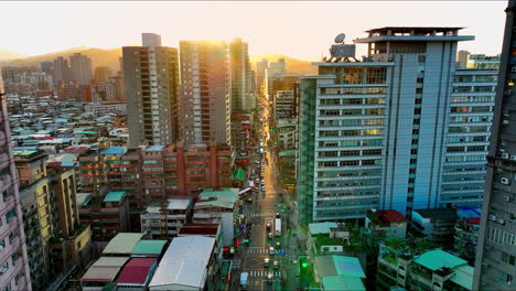 aerial flight between skyscraper apartments and traffic on road of taipei city at sunset