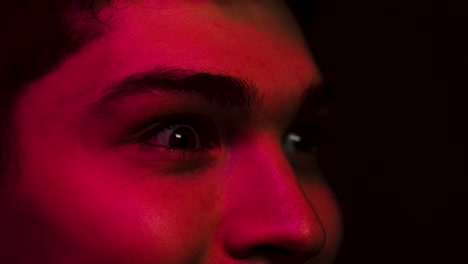 reacción conmocionada mientras la cara se ilumina en rojo, reaccionando a una película en el cine