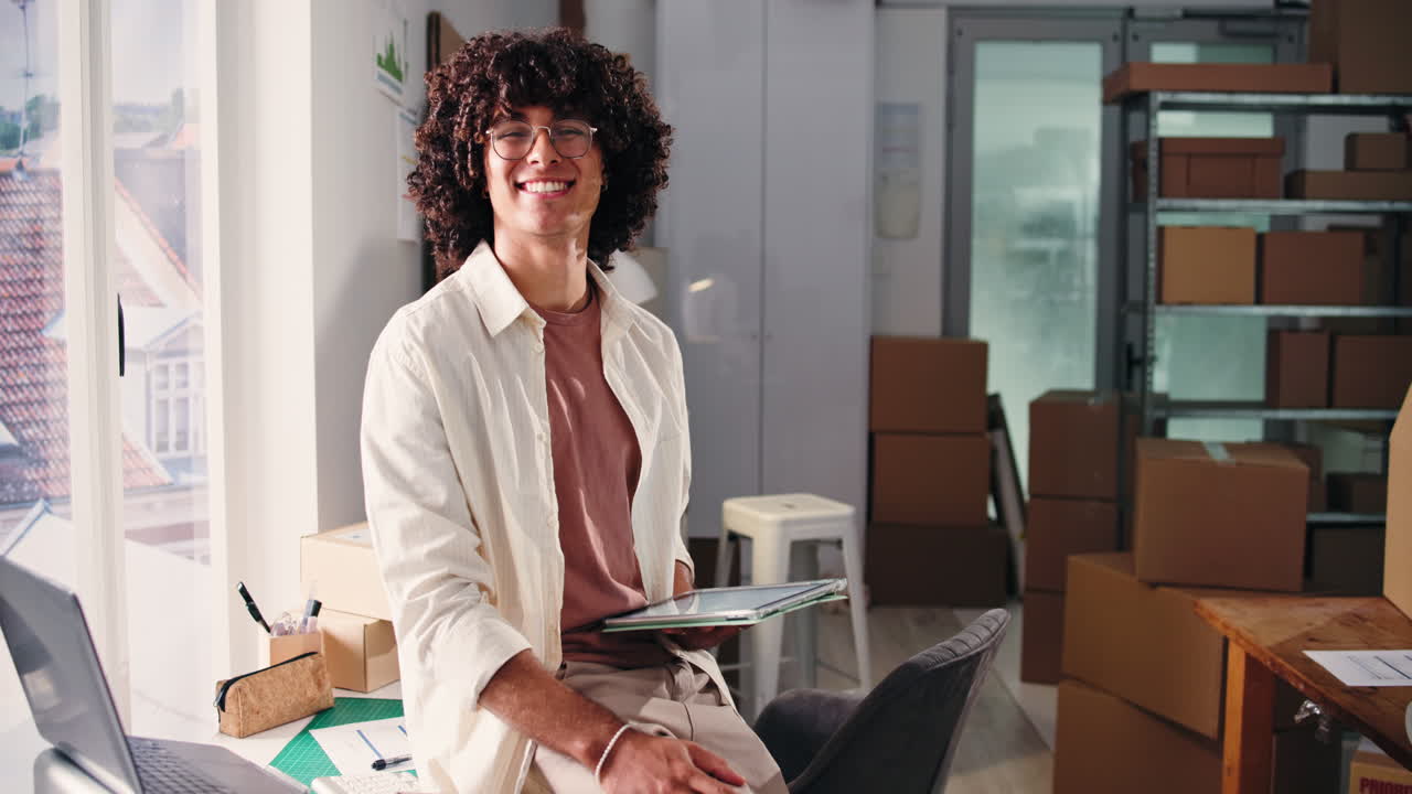 Jeune entrepreneur heureux travaillant sur tablette dans un bureau de petite entreprise.