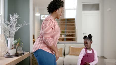 happy african american mother and daughter dancing at home, slow motion