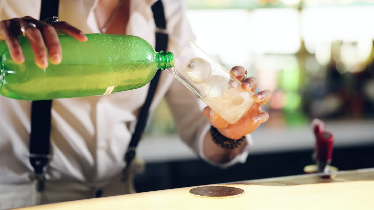 Barman che versa una bevanda da una bottiglia verde in un bicchiere con ghiaccio